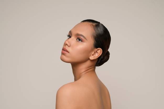 portrait d'un modèle de belle femme avec un maquillage quotidien frais et des sourires parfaits avec un beau visage sur un mur gris en studio