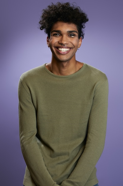 Portrait de modèle brune transgenre en t-shirt olive ressemble à la caméra et au sourire