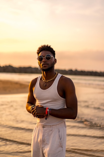 Portrait d'un modèle ethnique noir profitant de vacances d'été au bord de la mer portant des lunettes de soleil