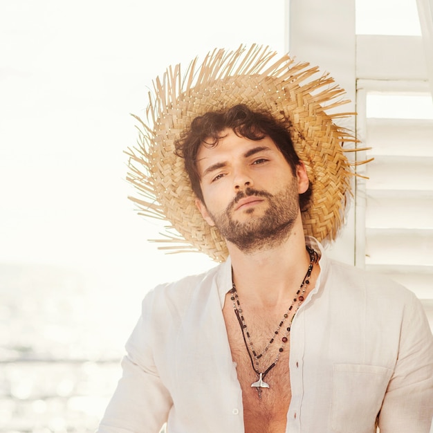 Portrait de modèle homme sexy vêtu d'un chapeau de paille et d'une chemise blanche, photo en plein air