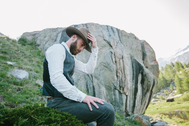 Portrait de modèle masculin beau hipster avec barbe portant des vêtements à la mode dans les montagnes