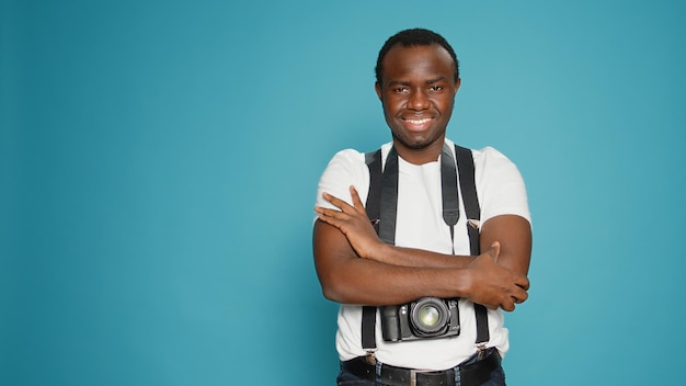 Portrait d'un modèle avec passe-temps photographique posant devant un appareil photo, utilisant un équipement professionnel pour capturer des images. Photographe assis les bras croisés pour prendre des photos en studio, art créatif.