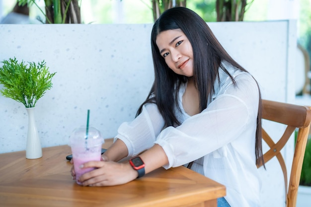 Portrait moderne d'une belle voyageuse asiatique heureuse portant une montre intelligente vêtue d'une belle robe blanche et portant un style de vie en jeans profitant d'un fond de restaurant de café assis