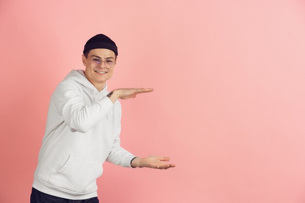 Portrait moderne du jeune homme caucasien sur studio rose