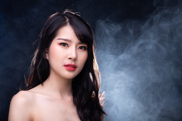 Portrait de la moitié du corps de 20 femme asiatique dans un style haute couture sur fond de brouillard de fumée avec éclairage rétroéclairé à l'arrière, copiez l'espace
