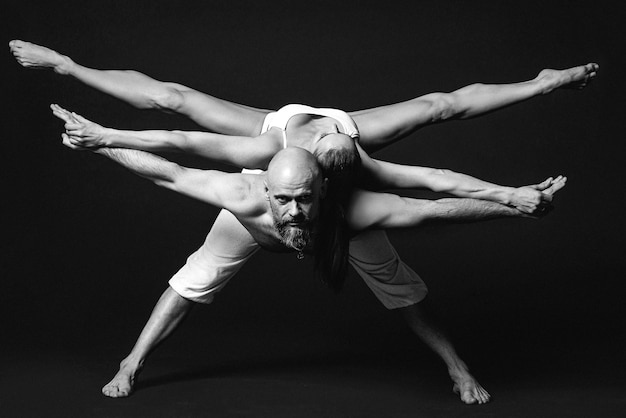 Portrait monochrome d'un beau couple sportif femme et homme en vêtements blancs faisant du yoga asana