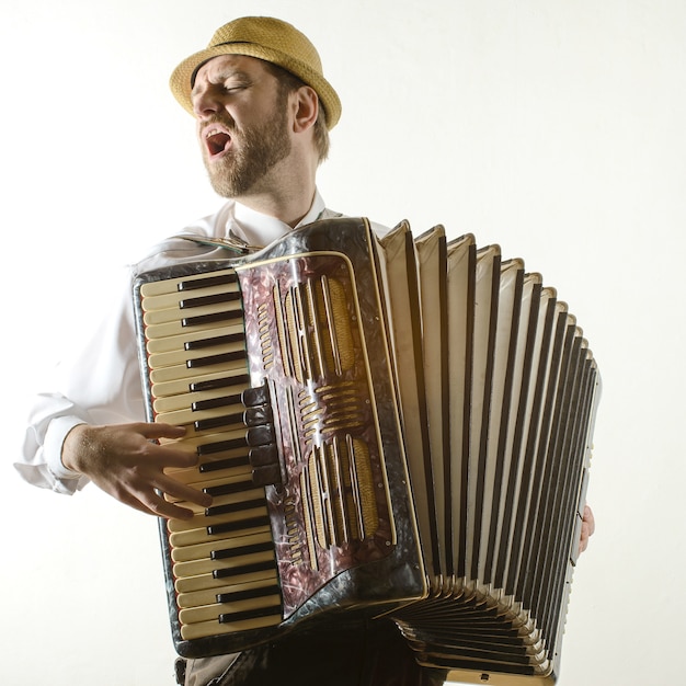 Photo portrait de musicien professionnel avec accordéon au mur blanc