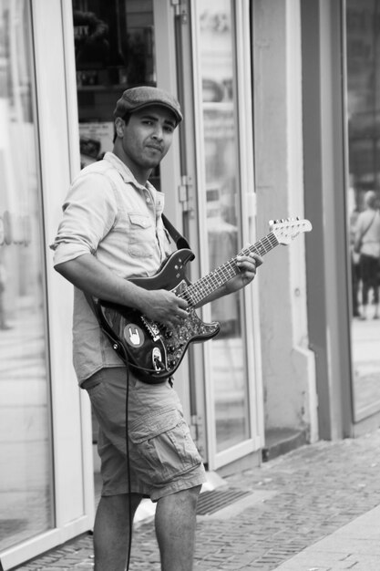 Photo portrait d'un musicien de rue jouant de la guitare électrique sur un trottoir