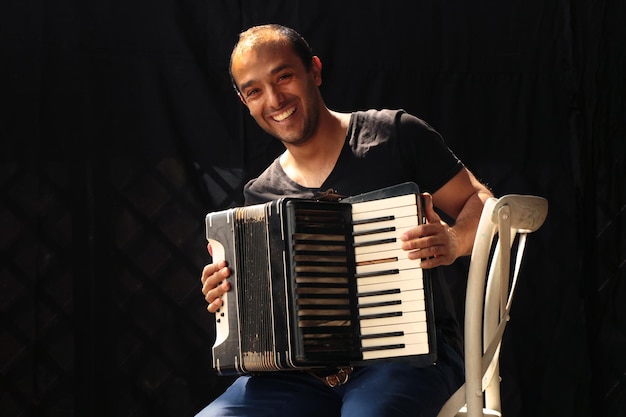 Photo portrait d'un musicien souriant jouant de l'accordéon sur scène