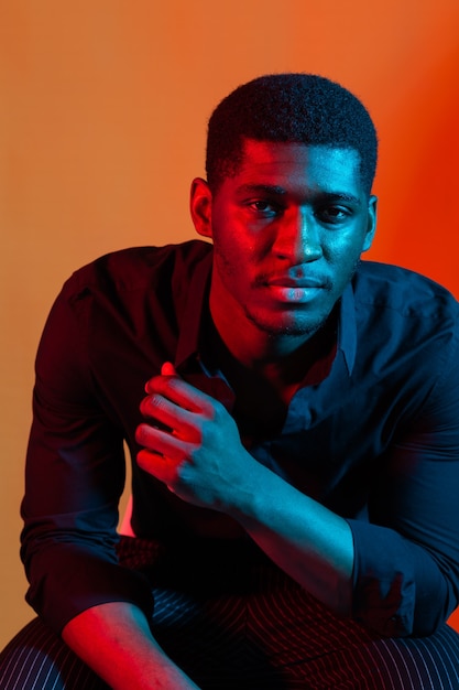 Portrait de néon sombre de jeune homme vêtu d'une chemise. Lumière rouge et bleue. La technologie