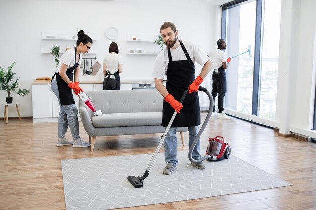 Portrait d'un nettoyeur professionnel barbu du service de nettoyage d'aspirateurs de tapis