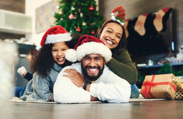 Photo portrait de noël et famille heureuse salon étage et sol célébration hivernale et amour soins et bonheur ensemble parents fille et enfant excité célèbrent des vacances festives dans le salon de la maison