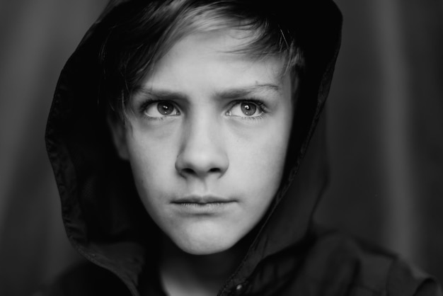 Portrait noir et blanc d'un adolescent sur fond sombre Gros plan discret d'un jeune garçon adolescent Photographie noir et blanc Mise au point sélective