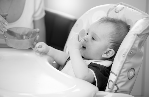 Portrait noir et blanc d'un bébé de 9 mois assis dans une chaise haute et jouant