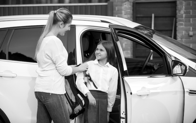 Portrait Noir Et Blanc D'une écolière Montant Dans La Voiture Et Donnant Un Sac à Sa Mère