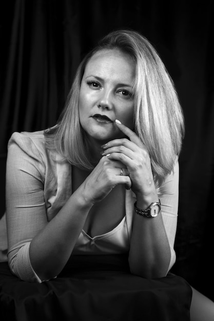 Portrait noir et blanc d'une femme d'affaires élégante avec un regard confiant dans le studio assis