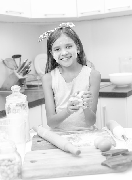 Portrait noir et blanc de fille préparant la pâte sur la planche en bois