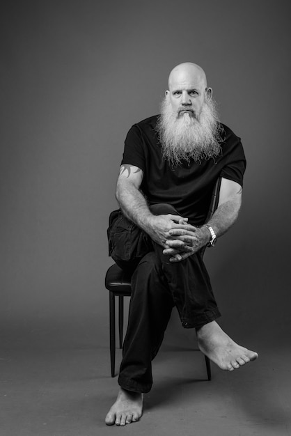 Portrait noir et blanc d'un homme chauve mature avec une longue barbe assis