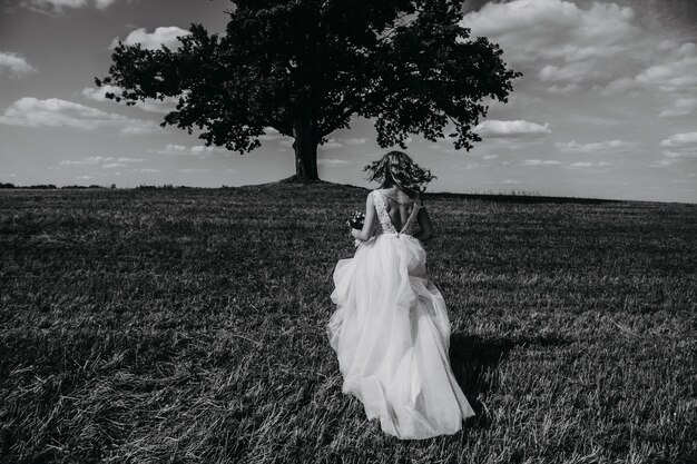 Portrait noir et blanc d'une mariée qui court dans un champ.