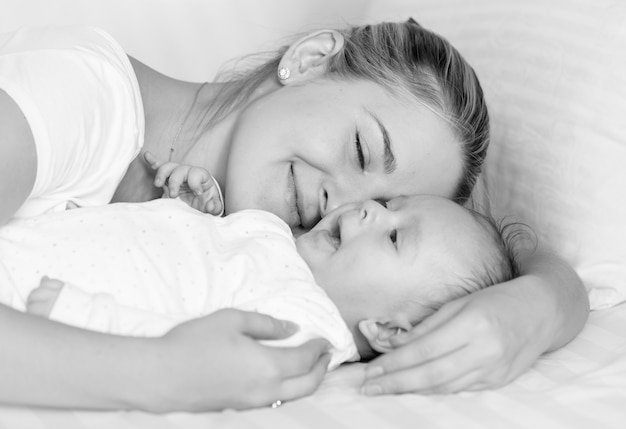 Portrait noir et blanc d'une mère joyeuse heureuse étreignant son bébé