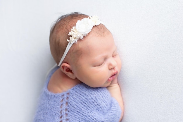 Portrait d'un nouveau-né endormi dans un costume tricoté sur fond blanc