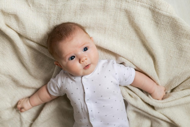 Portrait d'un nouveau-né mignon dans des vêtements légers allongé sur un couvre-lit en lin gris. produits pour enfants. concept de sommeil sain et de développement de l'enfant. enfance heureuse, maternité. Photo de haute qualité