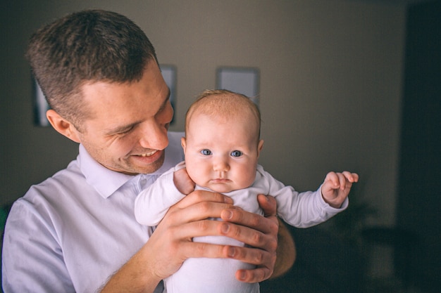 Portrait d'un nouveau-né. Le père tient un enfant dans ses bras. La première année de vie. Soins et santé