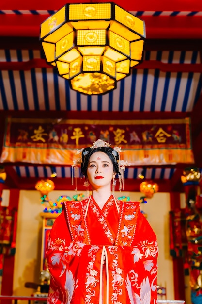 Portrait de nouvelle année d'une femme en costume traditionnel, d'une belle jeune femme en robe rouge vif et d'une couronne de reine chinoise.