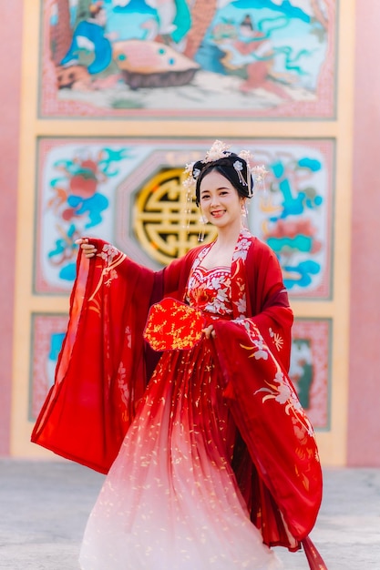 Portrait de nouvelle année d'une femme en costume traditionnel, d'une belle jeune femme en robe rouge vif et d'une couronne de reine chinoise.
