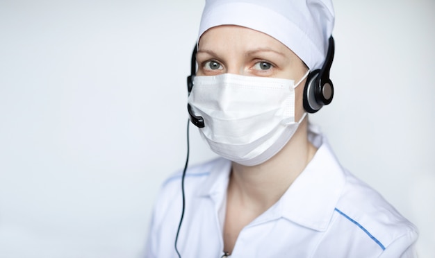 Photo portrait octor dans l'oreillette portant un masque de protection sur fond blanc, avec une zone de copie vierge pour le texte.