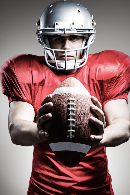 Portrait of American football player holding ball contre vignette grise