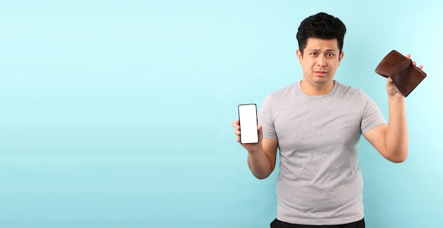 portrait of Asian man holding mobile phone un choqué, surpris sans voix. tenant un portefeuille vide en studio avec espace de copie.
