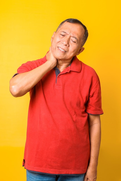 Portrait of Asian senior man souffrant de douleurs au cou sur fond de couleur jaune