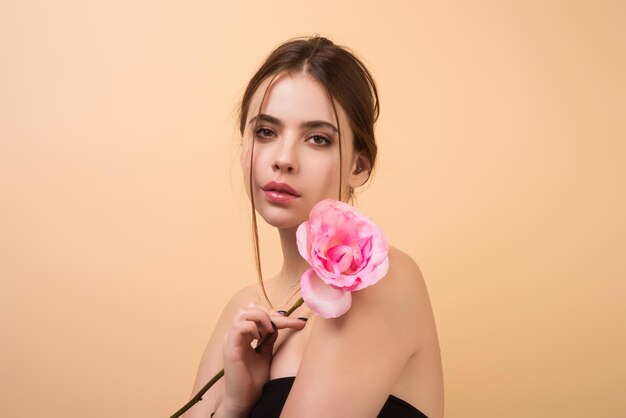 Portrait of attractive charmante charmante fille rêveuse tenant des roses rouges isolées sur fond de studio beige