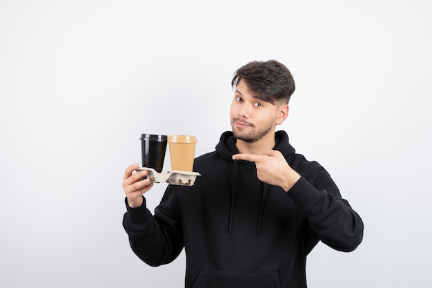 Portrait of attractive man montrant deux tasses à emporter dans un carton