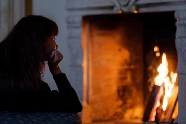 Portrait of attractive woman looking on fire rêvasser devant la cheminée