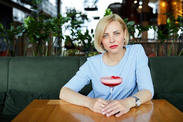 Portrait of attractive young woman drinking coctail in cafe indoor Belle femme blonde se détendre au bar et boire un cocktail