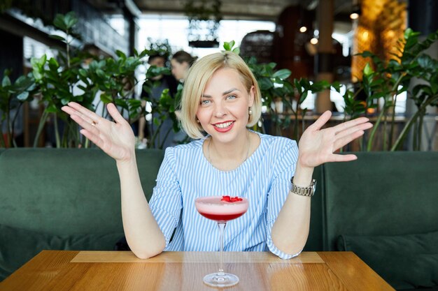 Portrait of attractive young woman drinking coctail in cafe indoor Belle femme blonde se détendre au bar et boire un cocktail