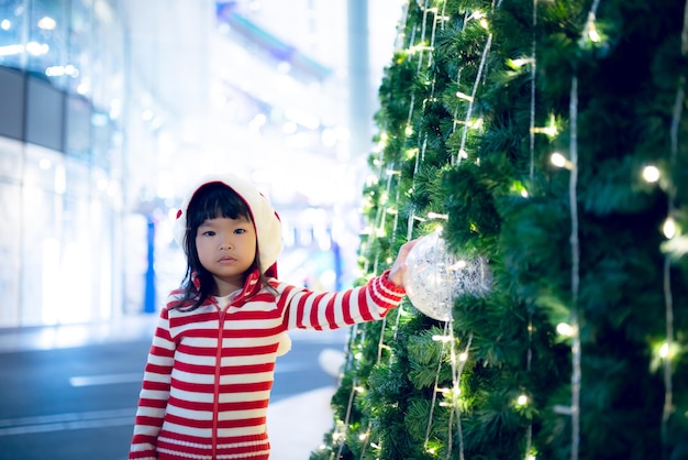 Portrait of cute asian little girl wear santa hat happy near christmas treeThailand kid rejoignez le festival de noël