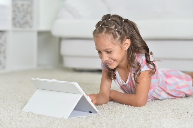 Photo portrait of cute girl with digital tablet on floor