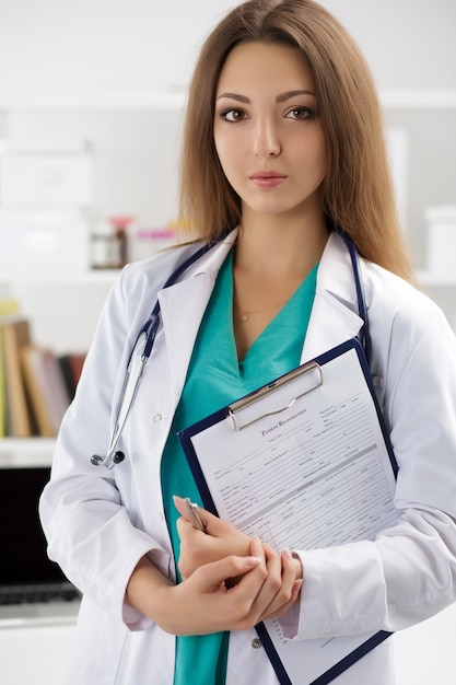 Portrait of female doctor holding clipping pad avec formulaire d'inscription du patient