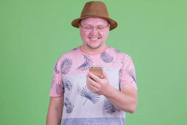 Portrait of handsome homme touriste barbu en surpoids contre chroma key ou mur vert