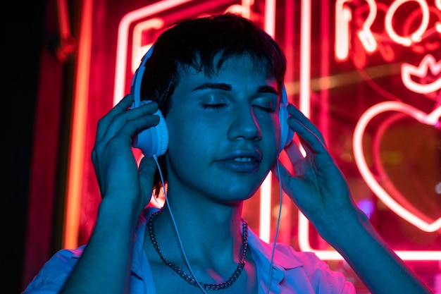 Portrait of Handsome Man Wearing Headphones Walking Through Night City Street Full of Neon Light