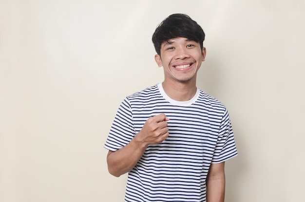 Portrait of happy Asian man pointing in tshirt rayé sur fond isolé