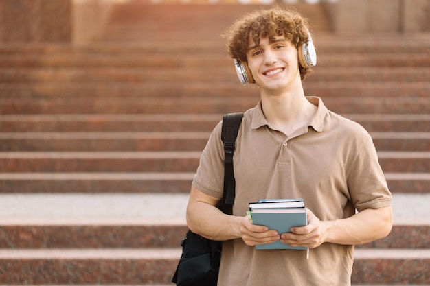 Portrait of happy attractive male student holding books et passé des examens à l'université