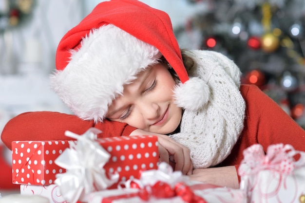 Portrait of happy girl in Santa hat dormir avec le cadeau de Noël