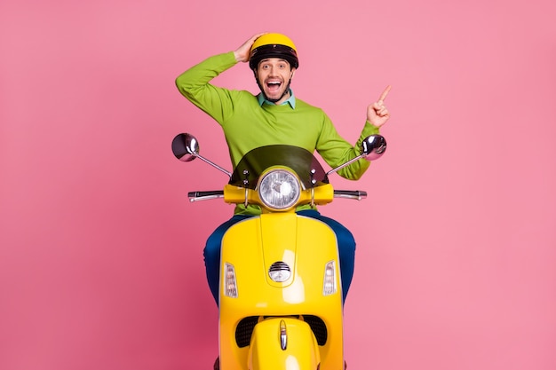 Photo portrait of happy guy équitation moto montrant une annonce