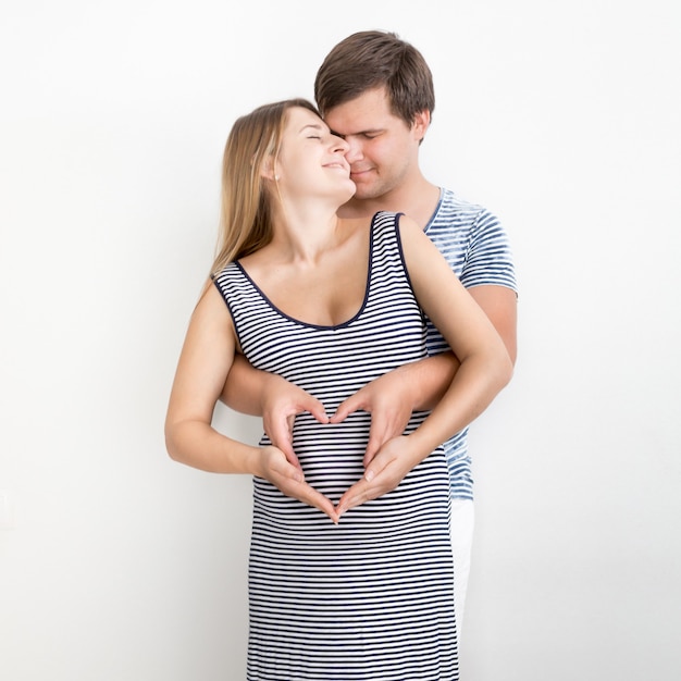 Portrait of happy hugging couple enceinte tenant la main en forme de coeur