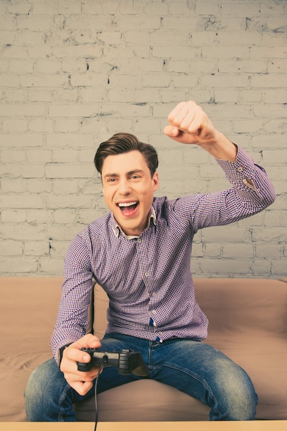 Portrait of happy man gagnant le jeu vidéo avec le poing levé