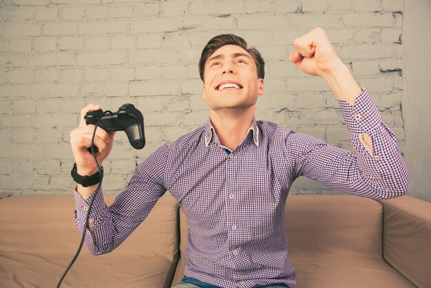 Portrait of happy man gagnant le jeu vidéo avec le poing levé